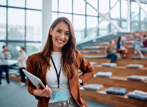 Happy female entrepreneur attending business seminar in conference hall and looking at camera.